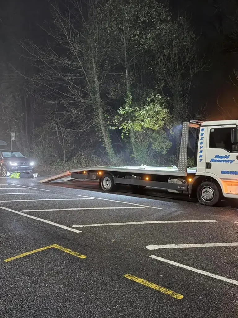 a tow truck with a flatbed trailer parked in a parking lot