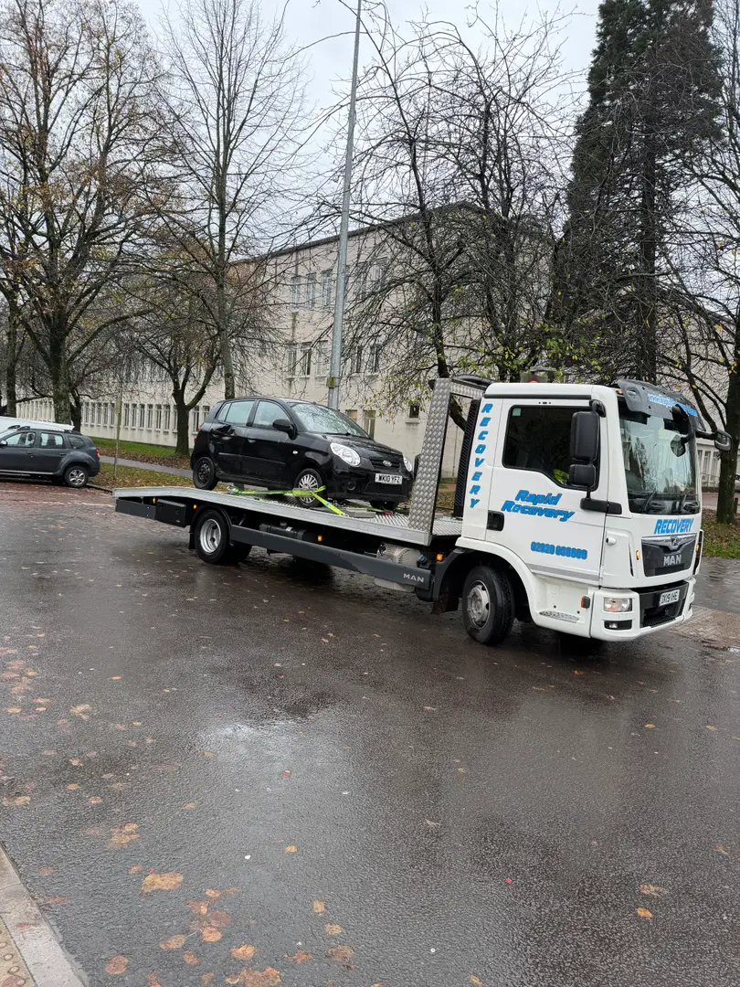a white truck with a black car on a road